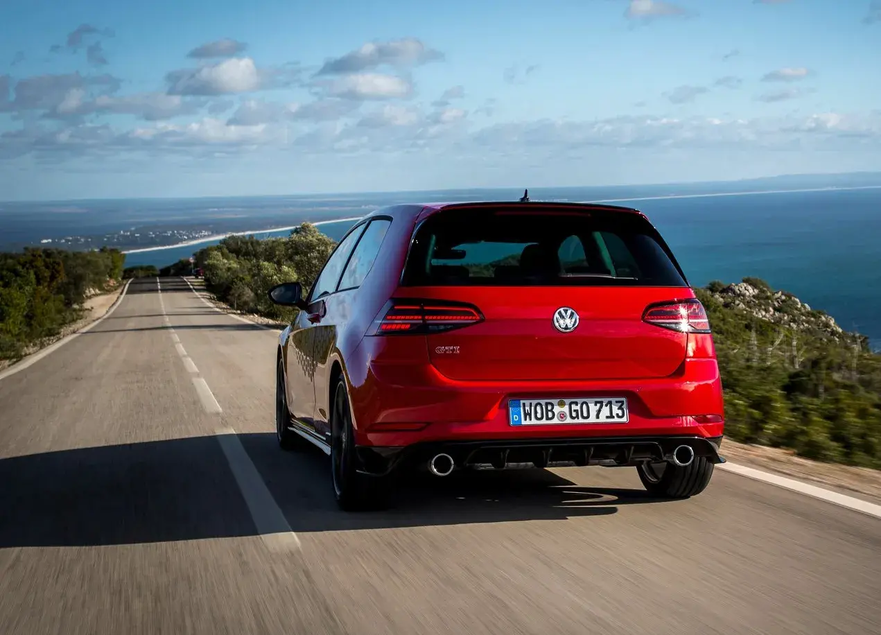 Volkswagen Golf GTI vermelho na estrada asfaltada e com céu azul ao fundo