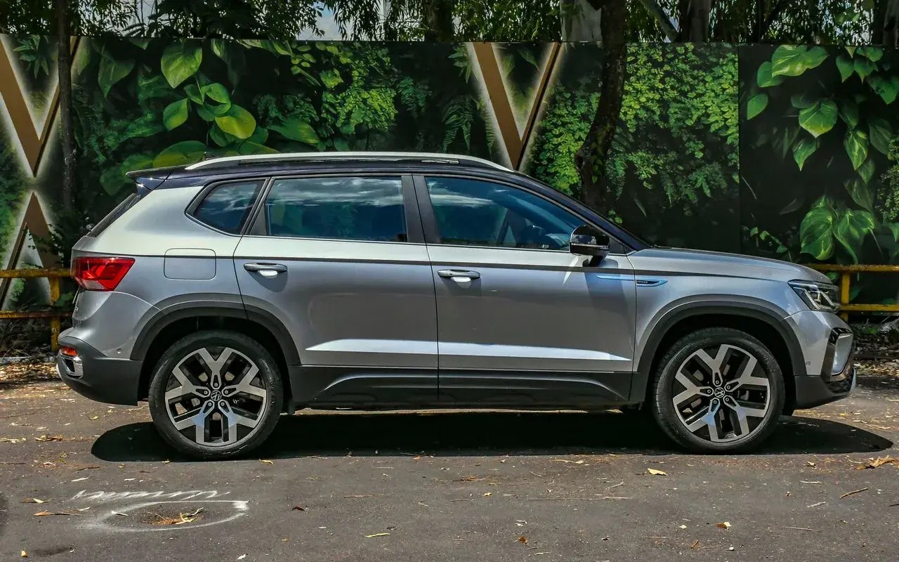 Volkswagen Taos 2025 prata com teto preto posicionado de lateral.