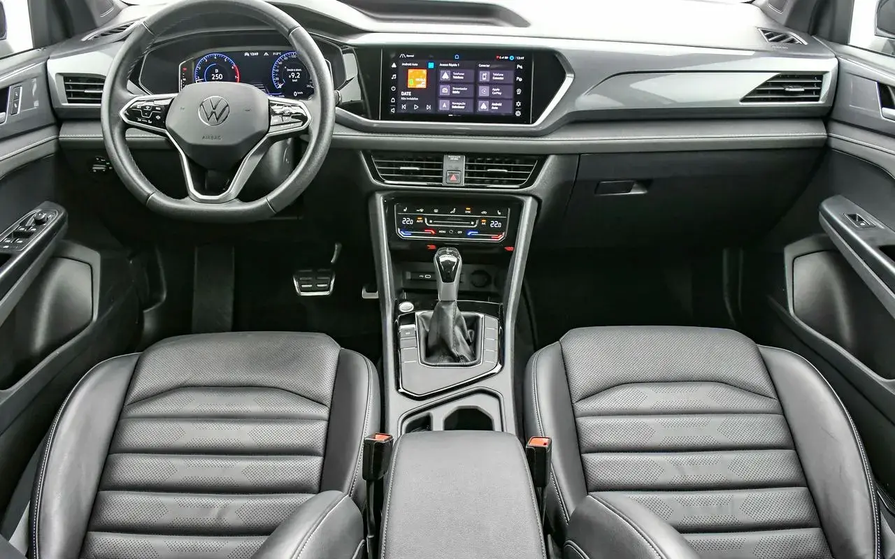 Interior do Volkswagen Taos 2025 mostra painel de instrumentos, central multimídia, bancos dianteiros e console central, onde está posicionado o câmbio